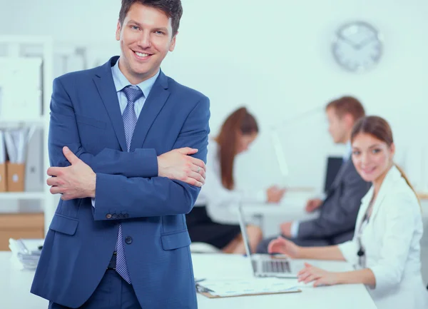 Succesvolle business man die met zijn personeel in de achtergrond op kantoor — Stockfoto