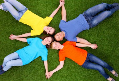 Bir grup genç insan yeşil çim üzerinde yalan