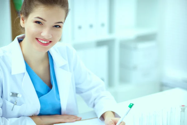 Woman researcher is surrounded by medical vials and flasks, isolated on white background — Stock Photo, Image