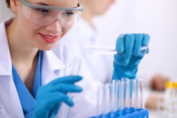 Woman researcher is surrounded by medical vials and flasks, isolated on white background — Stock Photo, Image