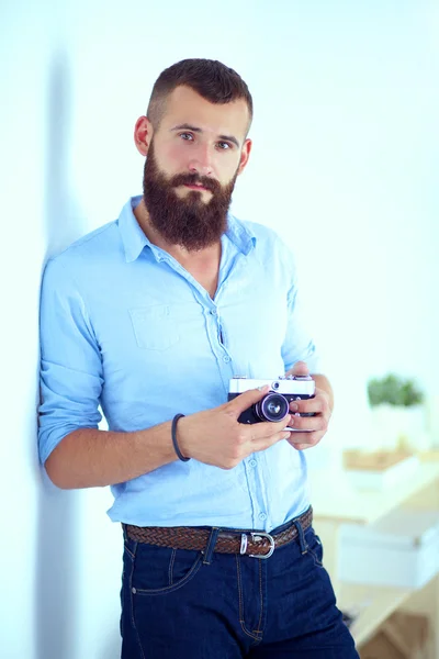 Jonge baard man met een camera terwijl staande tegen witte achtergrond — Stockfoto