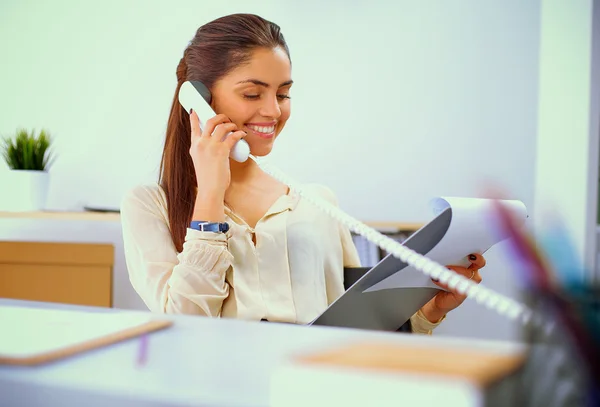 Jovem empresária sentada na mesa e conversando ao telefone — Fotografia de Stock