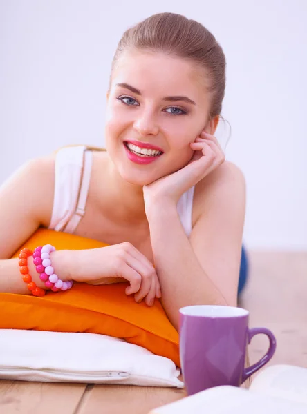 Mujer joven sonriente acostada en un suelo blanco con almohada —  Fotos de Stock
