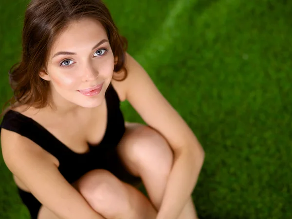 Mulher sentada com pernas cruzadas na grama verde — Fotografia de Stock