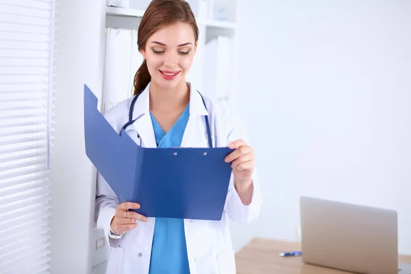 Young woman is standing in the near window with folder — Stock Photo, Image