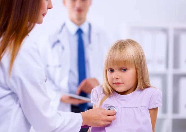 Female doctor examining child with stethoscope at surgery — Stock Photo, Image