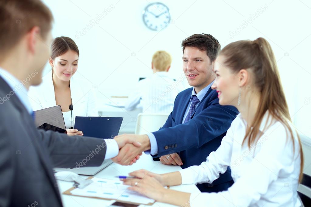 Business people shaking hands, finishing up a meeting, in office