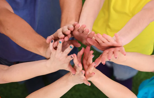 Lidé spojení jejich ruce na zelené trávě — Stock fotografie