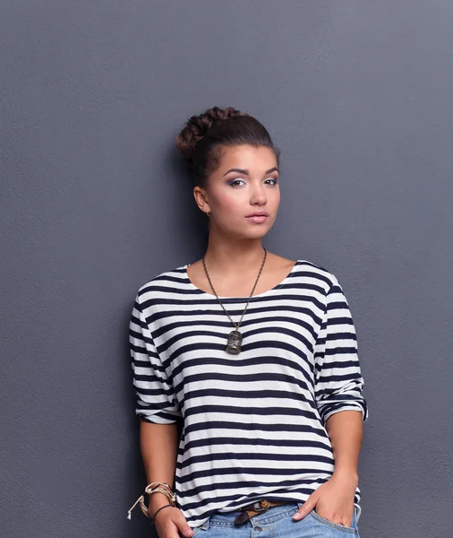 Young woman standing, isolated on gray background — Stock Photo, Image