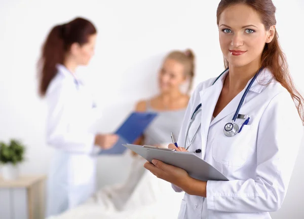 Smiling female doctor with a folder in uniform standing at hospital — Stock Photo, Image