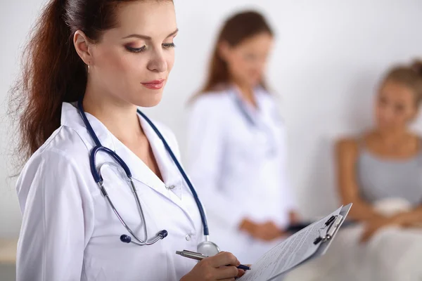 Sorridente medico donna con una cartella in uniforme in piedi in ospedale — Foto Stock