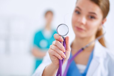 Steteskoplu kadın doktor dinliyor.