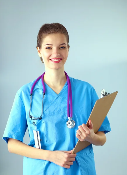 Médico sonriente con una carpeta en uniforme de pie en el hospital — Foto de Stock