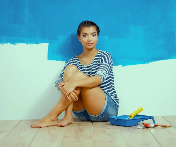 Retrato de pintora sentada en el suelo cerca de la pared después de pintar y sostener una taza —  Fotos de Stock