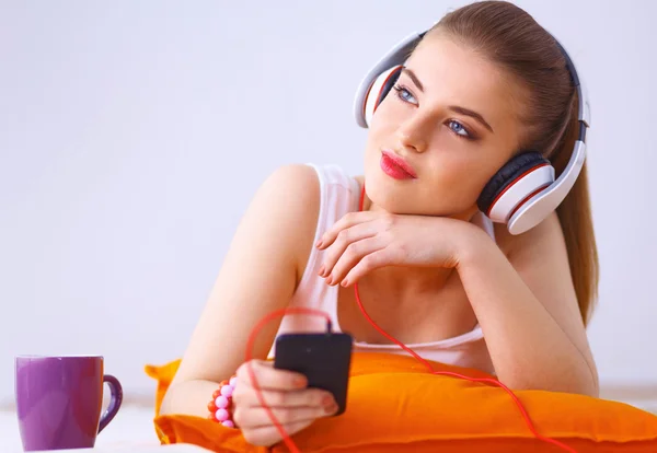 Молодая женщина лежит на полу и слушает музыку — стоковое фото