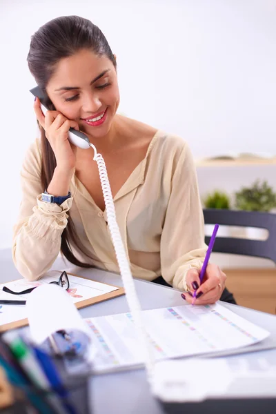 Młoda bizneswoman siedzi przy biurku i rozmawia przez telefon — Zdjęcie stockowe