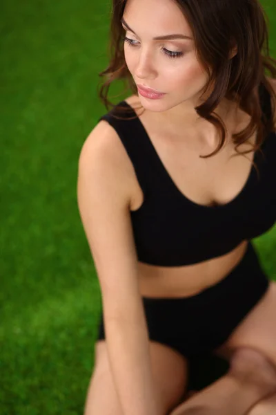 Young fitness girl sitting on green grass — Stock Photo, Image