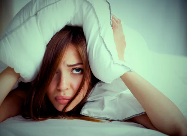 Mujer acostada en la cama y cerrando las orejas con almohada —  Fotos de Stock