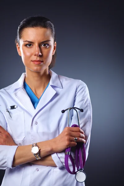 Retrato de una joven doctora sosteniendo un estetoscopio, aislada sobre fondo negro — Foto de Stock