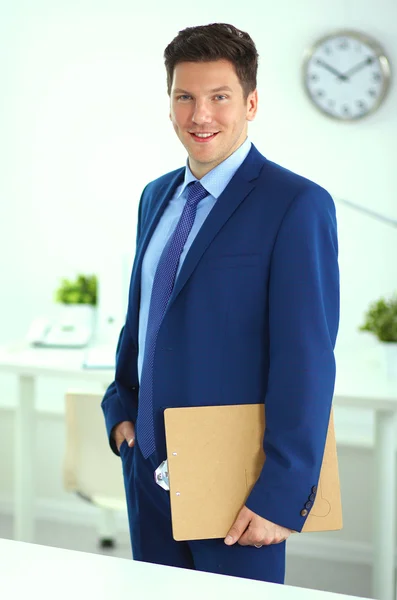 Zakenman of manager die op kantoor tegen zijn bureau staat — Stockfoto