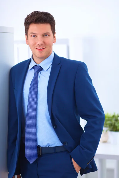 Homem de negócios ou gerente de pé contra sua mesa no escritório com os braços dobrados — Fotografia de Stock