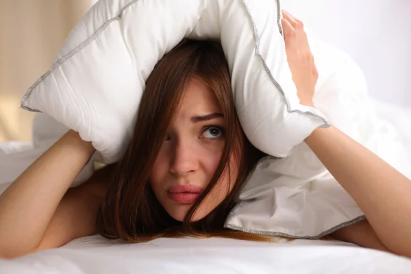 Mujer acostada en la cama y cerrando las orejas con almohada —  Fotos de Stock