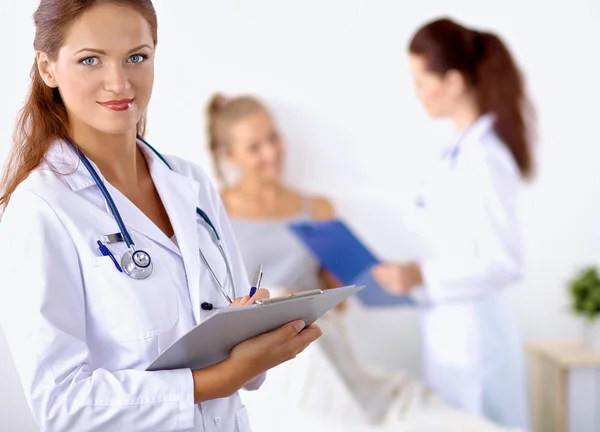 Médico sonriente con una carpeta en uniforme de pie en el hospital — Foto de Stock