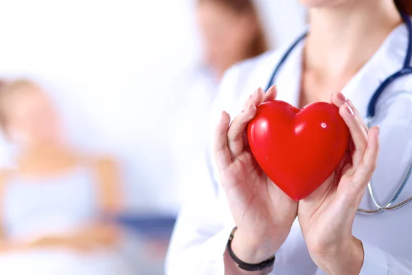 Mujer joven doctora sosteniendo un corazón rojo, aislado sobre fondo blanco — Foto de Stock