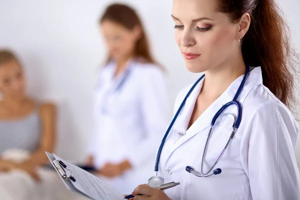 Sorridente medico donna con una cartella in uniforme in piedi in ospedale — Foto Stock