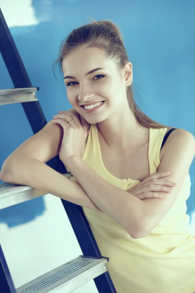 Feliz hermosa mujer joven haciendo pintura de pared, de pie cerca de la escalera —  Fotos de Stock