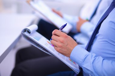 İş toplantılarında, ofiste oturan ve yazan iş adamları.