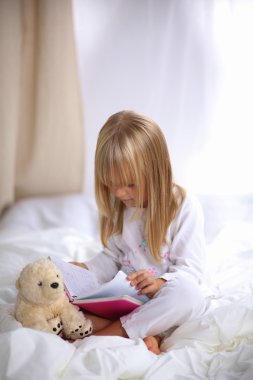 Küçük kız yatakta yatan ve bir kitap okuma