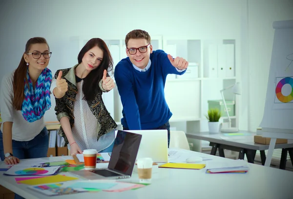 Young business people standing at office near desk and showing ok — Stock Photo, Image