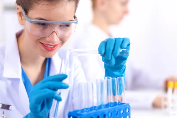 Woman researcher is surrounded by medical vials and flasks, isolated on white background — Stock Photo, Image