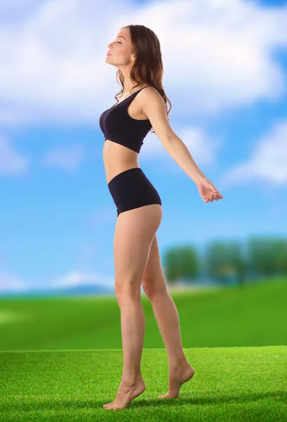 Молодая девушка фитнес стоя на зеленой траве — стоковое фото