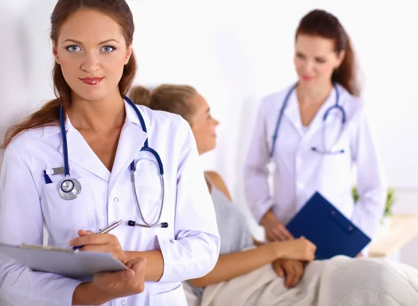 Médico sonriente con una carpeta en uniforme de pie en el hospital — Foto de Stock