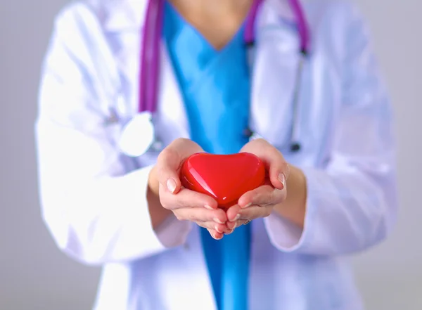 Mujer joven doctora sosteniendo un corazón rojo, parada en el hospital — Foto de Stock