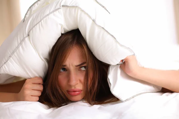 Mujer acostada en la cama y cerrando las orejas con almohada — Foto de Stock