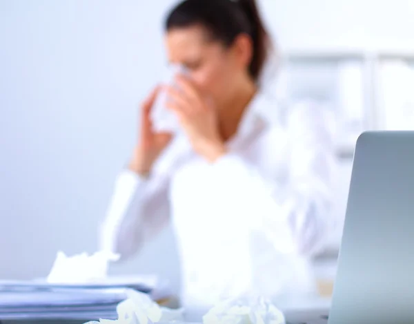 Young businesswoman blowing her nose, sits at the desk — Stock Photo, Image