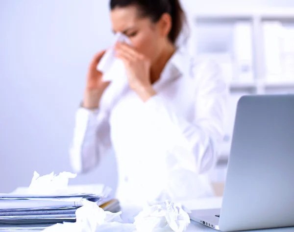 Junge Geschäftsfrau pustet sich die Nase, sitzt am Schreibtisch — Stockfoto