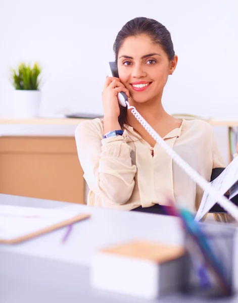 Jovem empresária sentada na mesa e conversando ao telefone — Fotografia de Stock