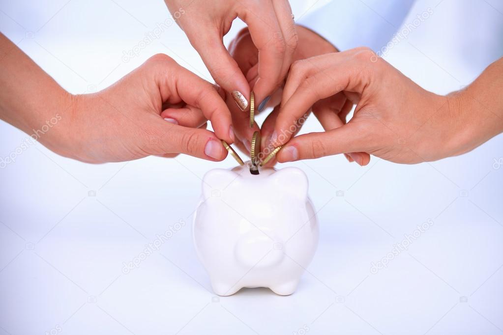 Putting coin into the piggy bank