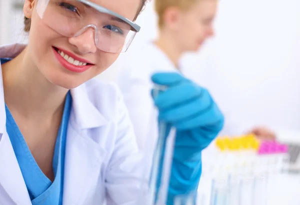 Woman researcher is surrounded by medical vials and flasks, isolated on white background — Stock Photo, Image