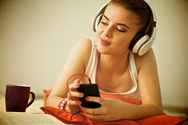 Mujer joven tumbada en el suelo y escuchando música — Foto de Stock