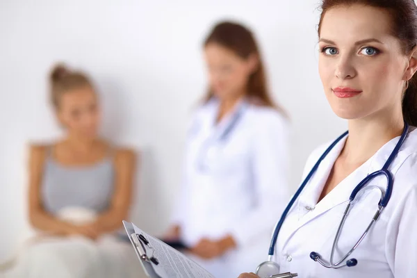 Médico sonriente con una carpeta en uniforme de pie en el hospital — Foto de Stock