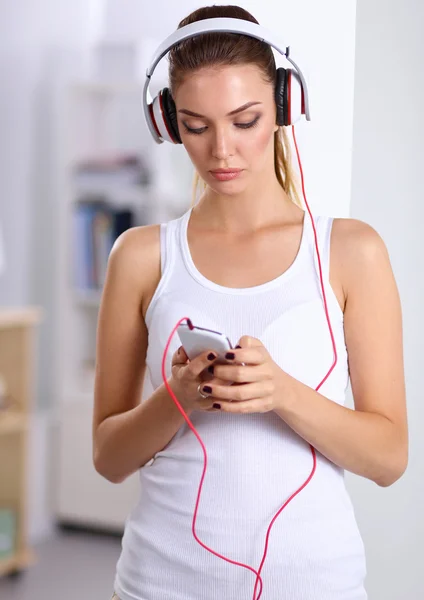 Femme avec casque écoutant de la musique debout à la maison — Photo