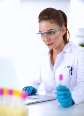 Kadın araştırmacı, beyaz şişeler ve şişelerle çevrili.