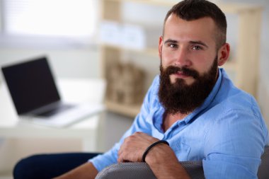 dizüstü bilgisayar ve bir çay bardağı evde oturan genç adam