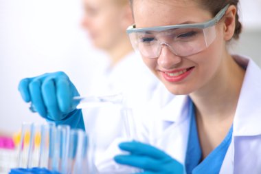 Kadın araştırmacı, beyaz şişeler ve şişelerle çevrili.