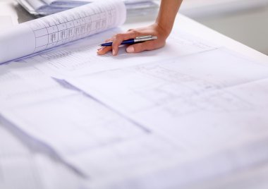Ofis masasında planları olan, izole edilmiş kadın mimarın portresi.